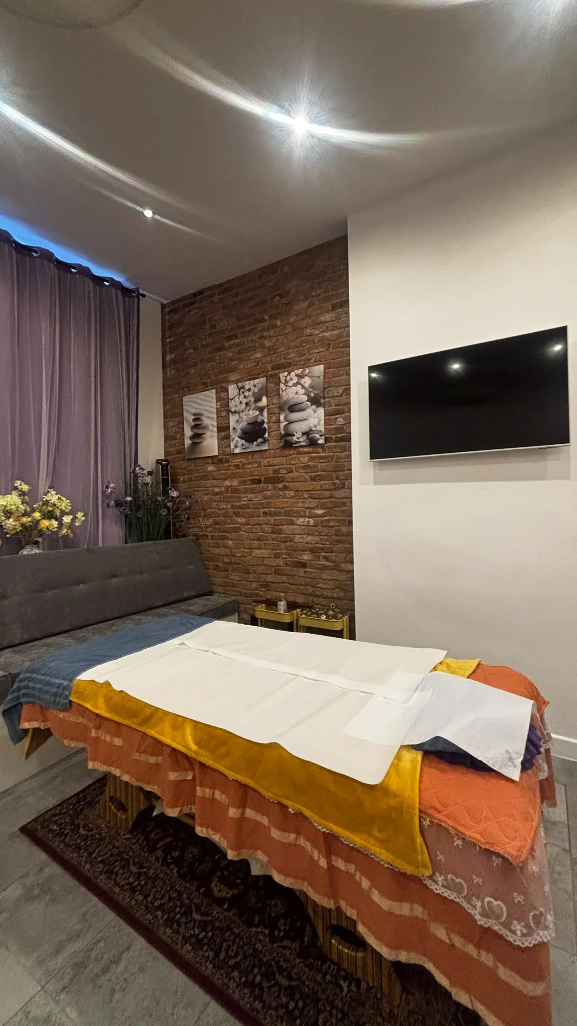 SUE's treatment table prepared inside the Portland Street practice, with seating, purple curtains and an exposed brick wall