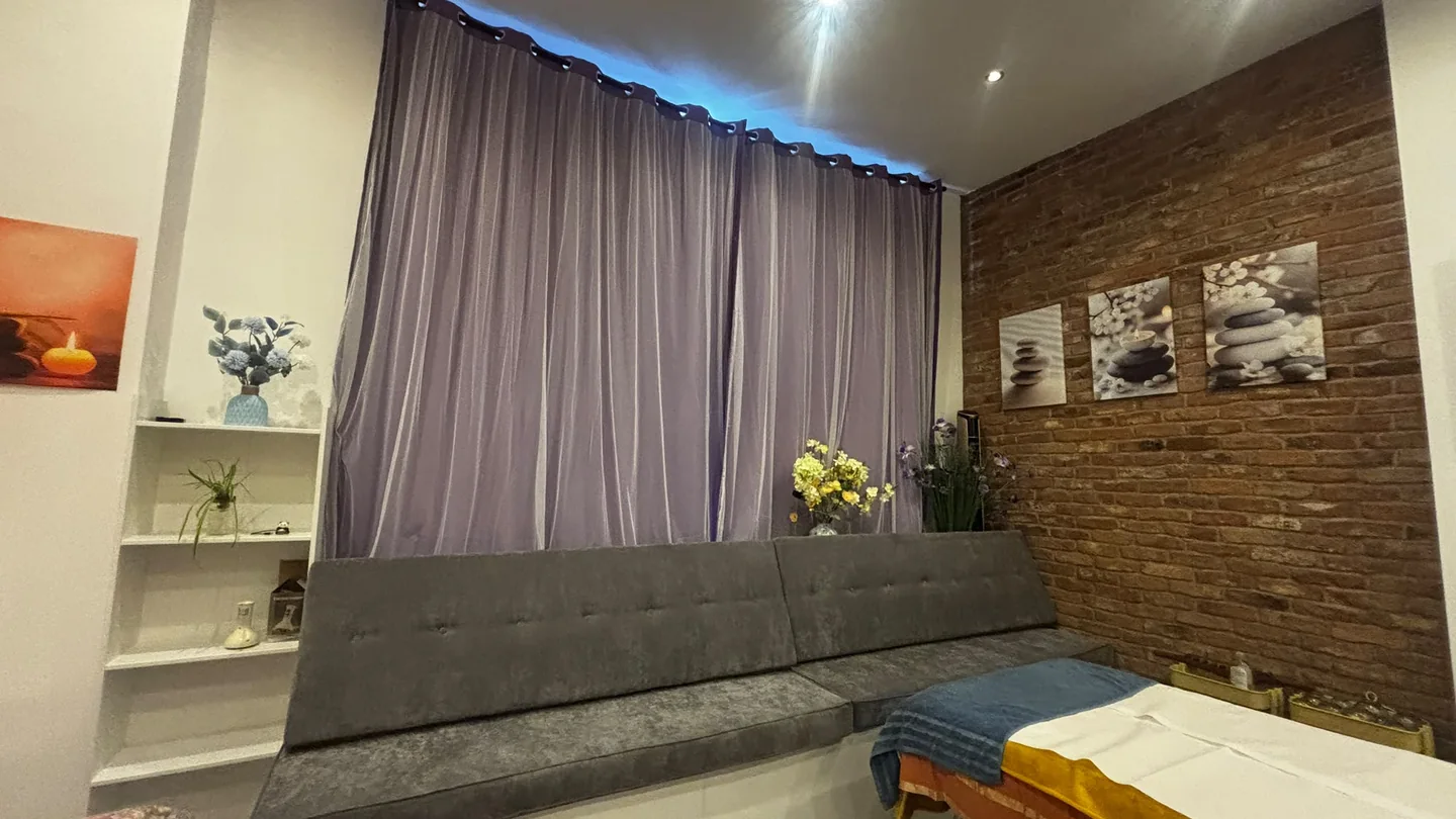 Wide view across the room showing the seating area, purple curtains and brick wall
